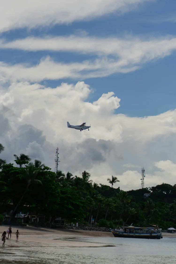 Aircraft on approach over a palm-fringed beach in the Cook Islands