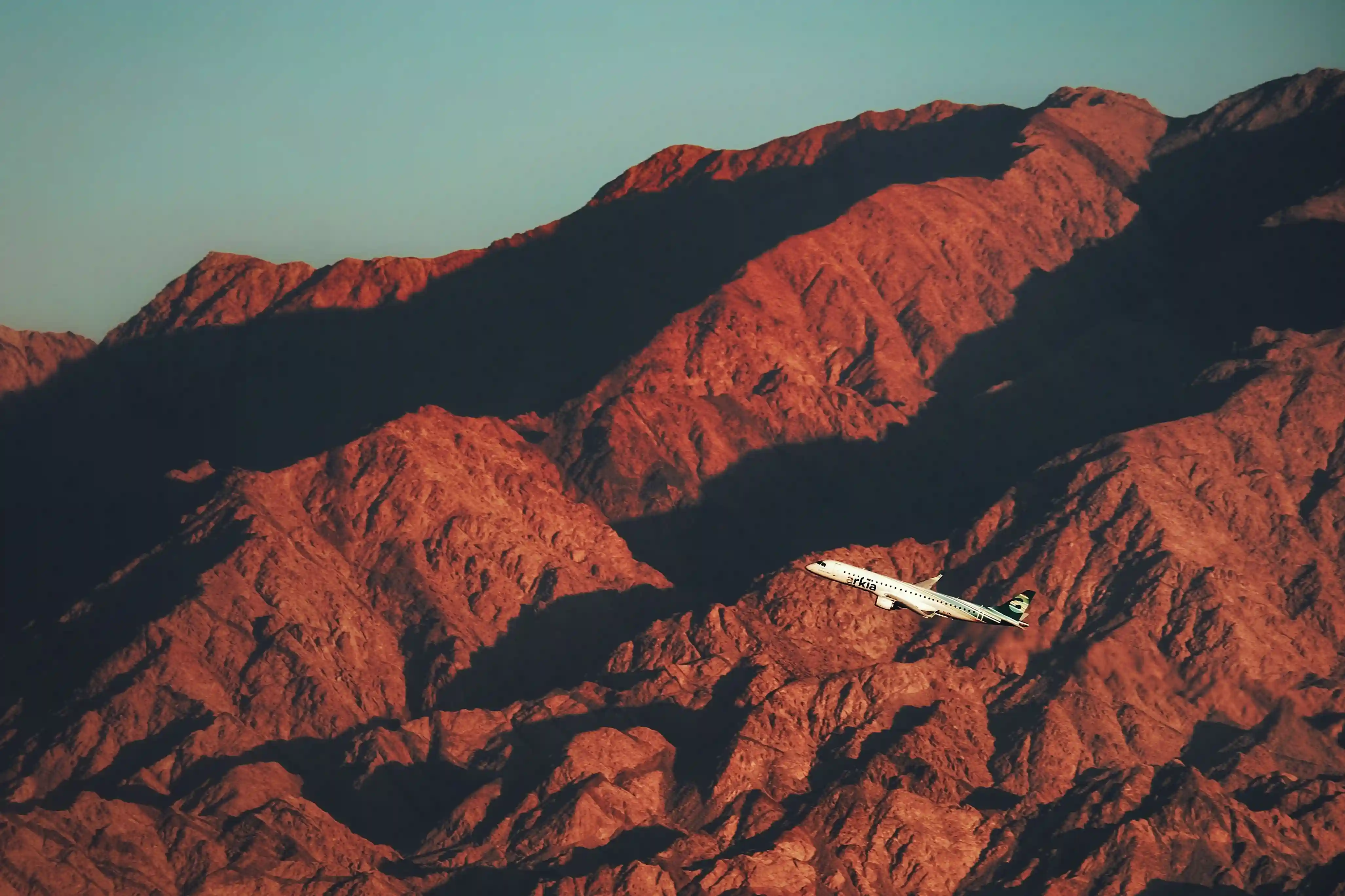 Aircraft in flight over red desert mountains